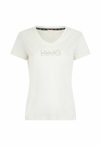 T-shirt en coton blanc avec un col en V, des manches courtes et le logo "kiddo" en studs argentés au centre devant. Texture lisse, style décontracté.