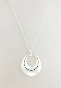 Silverfärgad hängande halsband med en cirkulär design och en inre svart accent. Kedjan är delikat med små länkar och har en polerad finish.