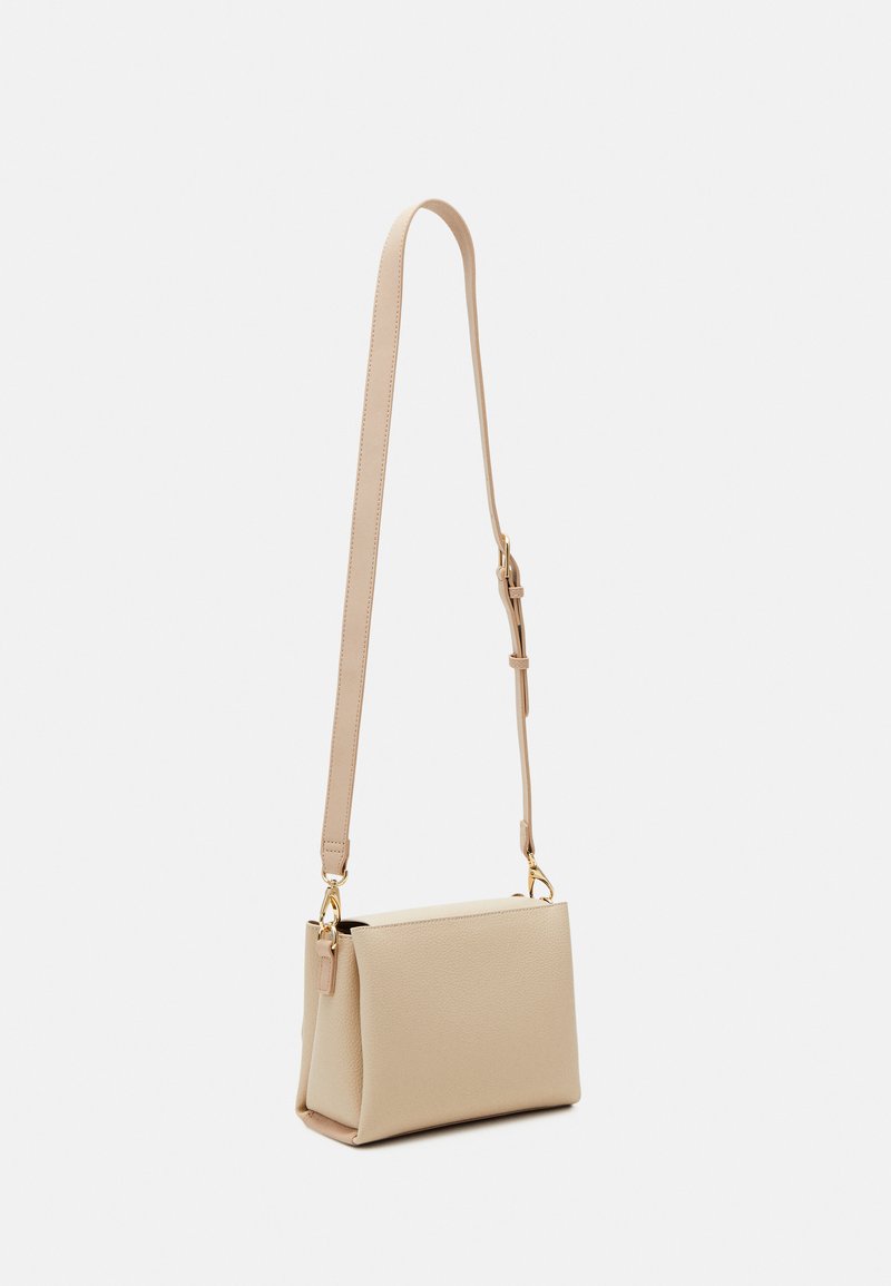 Sac bandoulière beige en matériau texturé, avec une forme rectangulaire, une sangle ajustable et des accents en métal doré.