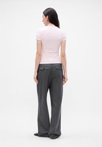 Hele roosa lihav särk lühikeste varrukatega, millele on juurde pandud hallid triibulised laiad püksid, millel on tagumised klapiga taskud.