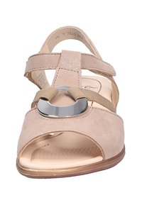 Beige Wildledersandale mit offenem Zehendesign, zwei Riemendetails, einem runden metallischen Akzent und einem gepolsterten Fußbett.