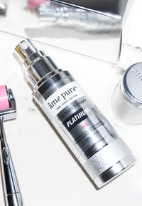 Kollagenterapigel i en silver- och svart pumpflaska. Har en metallisk yta och tryckt text. Inkluderar en dermaroller med rosa detaljer.