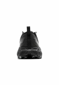 Zapatilla de correr negra con una parte superior de malla texturizada, collar acolchado y suela de goma con un patrón de banda de rodadura robusto. Lengüeta trasera para facilitar el calzado.