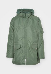 Grüne gesteppte Parka-Jacke mit fleecgefütterter Kapuze, Knopf- und Reißverschluss, zwei Fronttaschen und strukturierter Stoff.