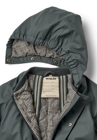 Tamsiai pilkas vandeniui atsparus švarkas su siuvinėtu keteriniu pamušalu. Savybė - nuimamas kapišonas ir raukšlėtas apykaklė. Viduje matomas etiketė.