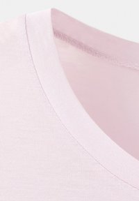 T-shirt en coton rose clair avec encolure montrant une fine couture côtelée du col et une texture de tissu lisse.