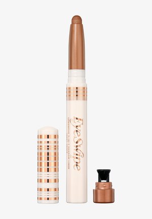 Krämig ögonskuggsstick med ett bronslock, som har en design med guld- och vitrandig mönstring. Applikatorn är slank och cylindrisk.