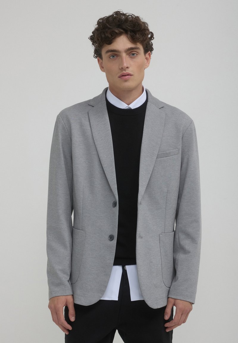 Grau blazer aus weichem Stoff mit tailliertem Schnitt, zwei vorderen Taschen, einer einzelnen Brusttasche und schwarzen Knopf-Akzenten.