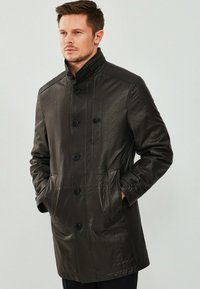 Donkerbruin leren jas met hoge kraag, knopen sluiting, zijzakken, gestructureerde afwerking en een getailleerde pasvorm.