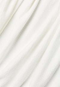 White fabric with a textured surface, featuring raised dots in a grid pattern. The material appears soft and slightly sheer.