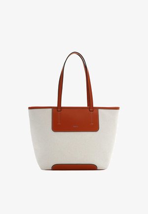 Sac fourre-tout en tissu beige avec anses en cuir marron, garniture assortie, et un écusson rectangulaire à l'avant portant un petit texte embossé.