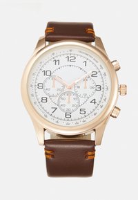 Reloj cronógrafo de oro rosa con una esfera blanca, correa de cuero marrón, tres subesferas y marcadores de hora en negro contrastantes. Asegurado con costuras naranjas.