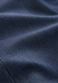 Marineblaue Denim-Stoff mit einer glatten Textur, der feine, diagonale Webmuster und einen leichten Glanz im natürlichen Licht aufweist.