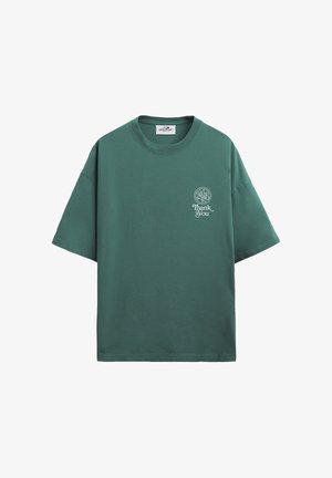 Grønn oversized T-skjorte med korte ermer, hvit sirkulær logo og teksten "Thank You" på venstre bryst, ensfarget bakgrunn.