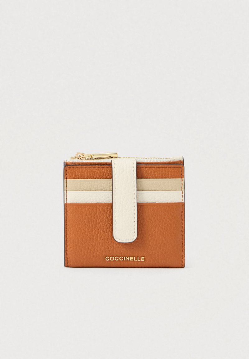 Compact brown leather wallet with beige and white horizontal stripes, gold zipper, and front strap closure embossed with brand name.