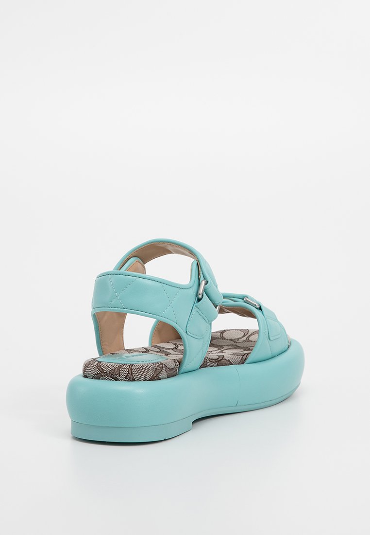 Błękitne sandały wykonane z gładkiego materiału syntetycznego. Posiadają pikowaną konstrukcję paska, regulowany zamek i wzorzystą wkładkę. Gruba podeszwa.