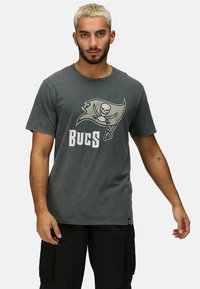 Šedé bavlněné tričko s logem Buccaneers a textem níže. Krátké rukávy, kulatý výstřih a měkká, opotřebovaná textura.