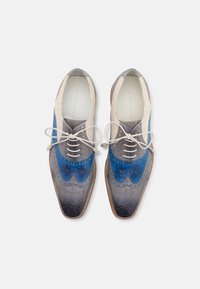 To-farget brogue-sko i kombinasjonen marineblå og grå lær, med perforerte detaljer, spiss tå og beige detaljer.
