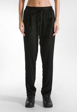 Schwarze, gerippte Velour-Hosen mit elastischem Bund und Kordelzug. Lockere Passform, mit Seitentaschen und glatter Textur.