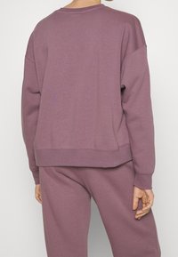 Lila sweatshirts med avslappnad passform, rund hals och ribbad nederkant. Tillverkad av mjukt material, med sänkta axlar och en enkel design.