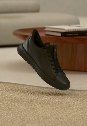 Sneaker in pelle nera con punta arrotondata, suola in gomma strutturata e lacci piatti. Caratterizzato da un design minimalista e un marchio discreto.