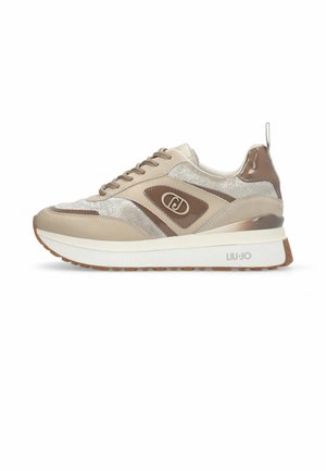 Beige-brauner Schnür-Sneaker mit dicker weißer Sohle, strukturierten Stoffpaneelen und Logoemblem an der Seite und der Sohle.