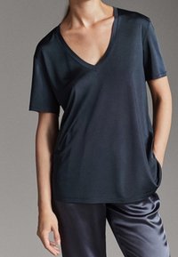 Dark navy V-neck T-shirt made of smooth, lightweight fabric. Short sleeves and relaxed fit, with subtle sheen and side pocket detail.