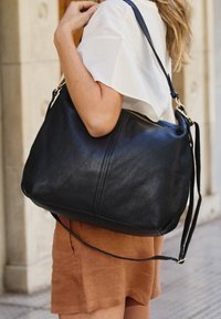 Borsa a tracolla in pelle nera con finitura testurizzata, dotata di chiusura con zip, tracolla lunga e dettagli di cuciture sottili.