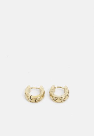 Brincos de argola em ouro com um design texturizado, apresentando a gravação da palavra "GUESS" e pequenas pedras decorativas. Formato circular e acabamento polido.