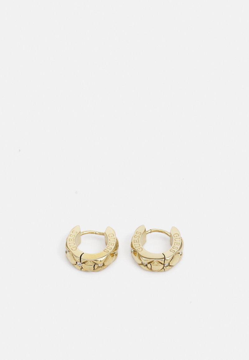 Gouden hoepel oorbellen met een gestructureerd ontwerp, voorzien van gegraveerde "GUESS" letters en kleine decoratieve stenen. Cirkelvormig en met een gepolijste afwerking.