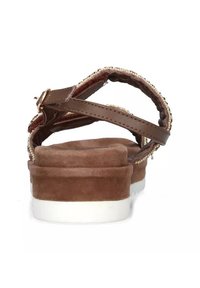 Sandali in suede marrone con cinturini incrociati e suola imbottita. Il tacco presenta una base in gomma bianca e decorazioni di perline lungo i cinturini.