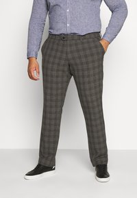 Grijze geruite broeken van een gladde stof, met een rechte voorkant, zijzakken en een slim fit ontwerp. Gemaakt met een blauwe shirt en zwarte sneakers.