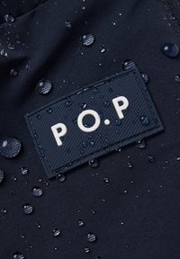 Marine stof met een gestructureerd oppervlak, met een rechthoekig etiket met "P.O.P" in witte letters en waterdruppels op het oppervlak.