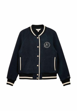 Navy blue fleece varsity jacket featuring a round logo patch, cream accents, ribbed collar and cuffs, snap button closure, and side pockets.