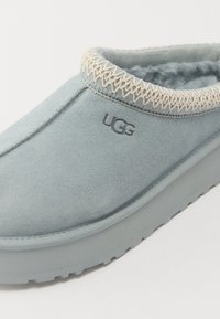 Lichtblauwe suède instapschoen met een ronde neus, textuur trim en UGG-logo, met een zachte binnenkant en een stevige rubberen zool.