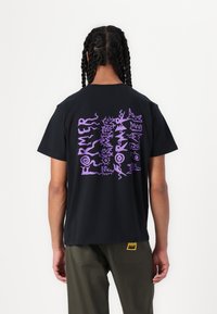Zwarte katoenen t-shirt met een groot paars grafisch tekstontwerp op de rug. Korte mouwen, ronde hals en een relaxte pasvorm.