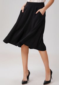 Jupe noire en A avec une taille haute, deux poches latérales et un design fluide ; tissu lisse avec une texture douce.