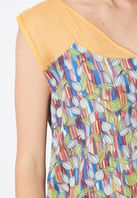 Top sin mangas con estampado que presenta un vibrante diseño floral en azul, verde y naranja, con un suave acento de tela amarilla en el hombro.