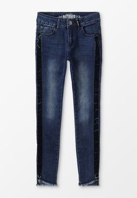 Jeans de mezclilla azul oscuro con corte ajustado, que cuentan con franjas laterales de terciopelo negro y un dobladillo deshilachado. Dos bolsillos delanteros y una etiqueta en la cintura.