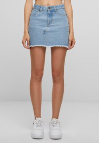 Lyseblå denim miniskjørt med rå kant, tettsittende design, fem-lomme styling og knappelukking foran. Brukt med hvite joggesko.