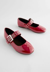 Rote Lackleder-Mary-Jane-Schuhe mit quadratischer Spitze, ausgestattet mit einem breiten Riemen mit metallischen Ösen und einer silbernen Schnalle.