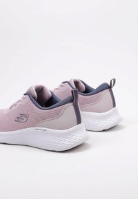 Un paio di sneaker Skechers Skech-Lite rosa e grigie con suole bianche testurizzate su uno sfondo bianco, viste da dietro e di lato.