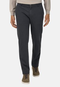 Tumši pelēki chinos, kas izgatavoti no kokvilnas, ar taisnu griezumu, ar priekšējo pogu aizdari un sānu kabatām, kombinēti ar olīvu zaļiem augstiem sporta apaviem.