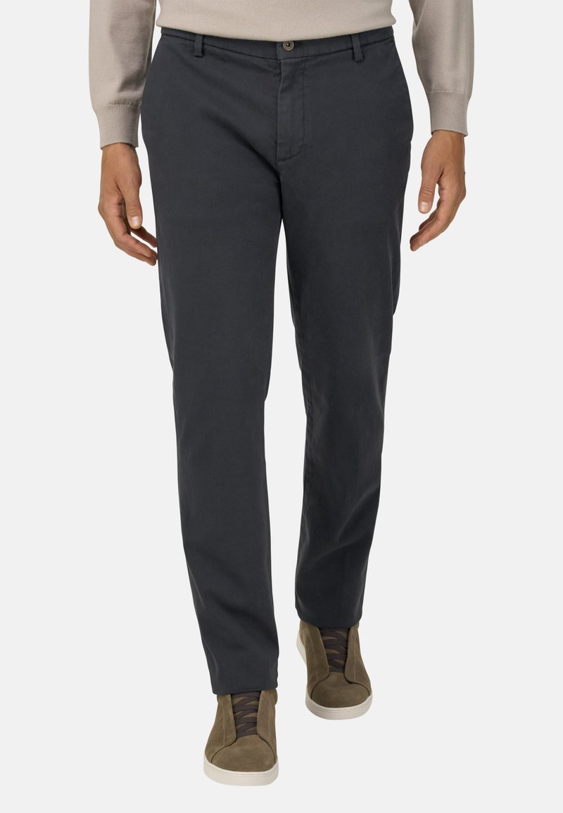 Tumši pelēki chinos, kas izgatavoti no kokvilnas, ar taisnu griezumu, ar priekšējo pogu aizdari un sānu kabatām, kombinēti ar olīvu zaļiem augstiem sporta apaviem.