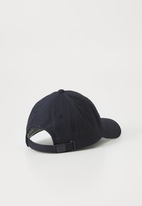 Navy blue baseball cap made of cotton with a rounded crown, curved visor, adjustable strap, and ventilation holes on the back.