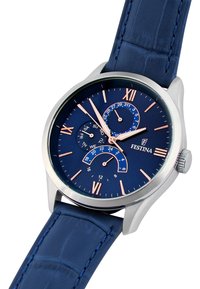 Herrklocka med marinblå läderrem, hölje i silverfärgad rostfritt stål och blå urtavla med romerska siffror och datumindikatorer.