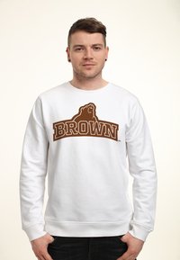 Witte sweatshirt met een grafisch ontwerp van een bruine beer en de tekst "BROWN" in vette letters. Lange mouwen en geribbelde manchetten met een klassieke pasvorm.