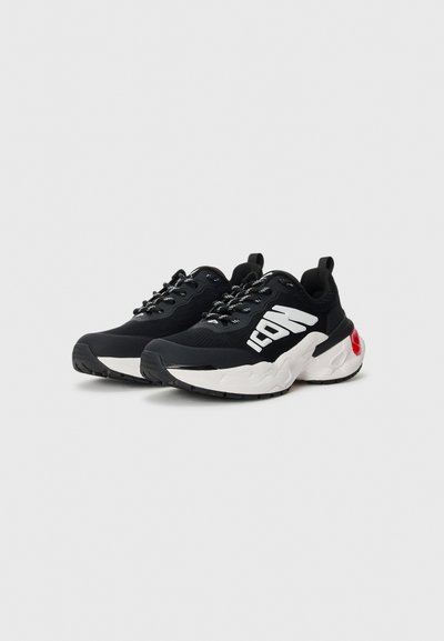 Black athletic shoes with a mesh upper, white accents, and a textured sole. Features laces and a red detail on the heel.
