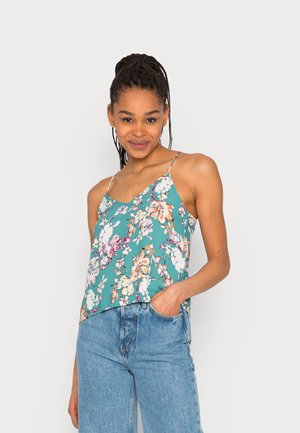 Camisola floral em tecido teal com alças finas, apresentando uma mistura de flores rosa, brancas e laranjas; corte descontraído, combinada com jeans azul claro.