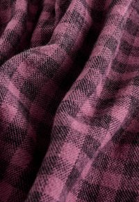Tissu texturé dans un motif à carreaux noir et rose foncé, avec un tissage doux qui crée de délicates plis et une surface légèrement duveteuse.